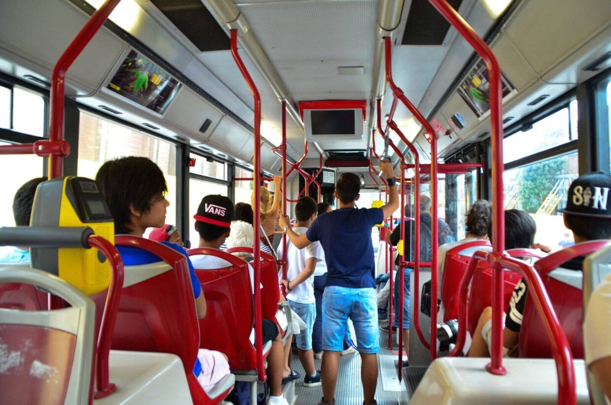 Inside view of a city bus in Rome with seated and standing passengers.
